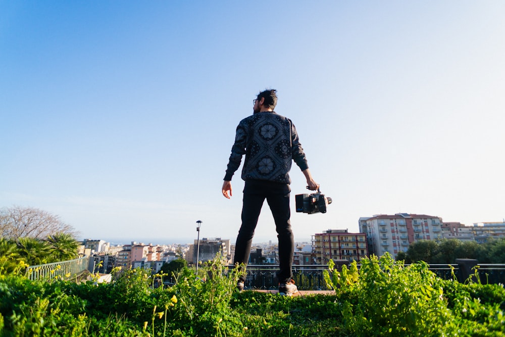 man in black and gray long sleeve shirt standing on green grass field during daytime