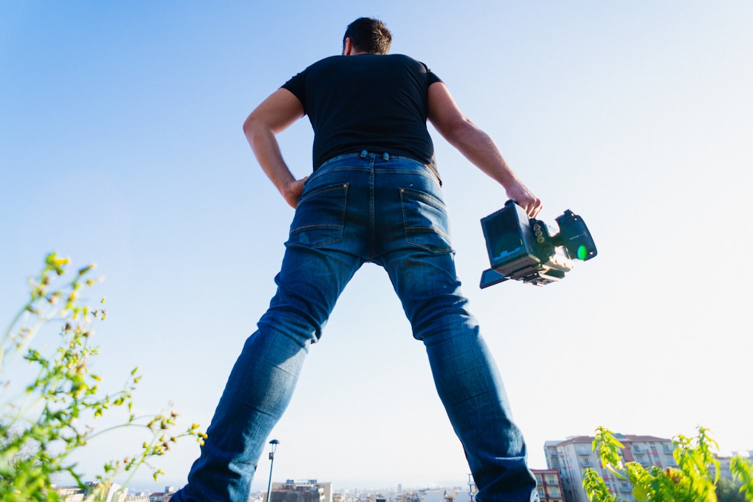 man in black t-shirt and blue denim jeans holding green and black plastic container