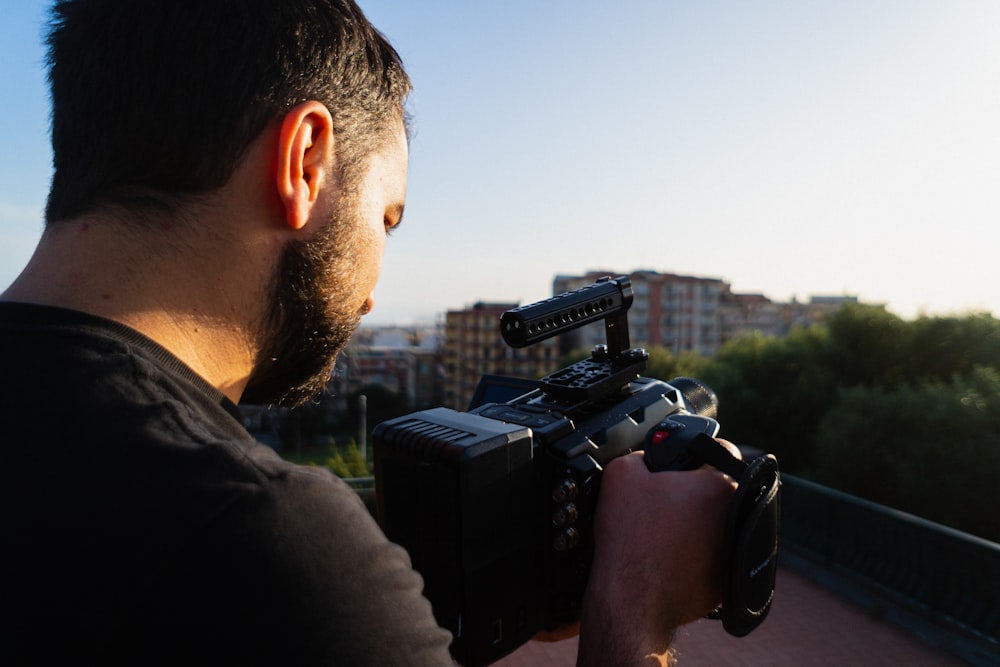 man in black shirt holding black dslr camera