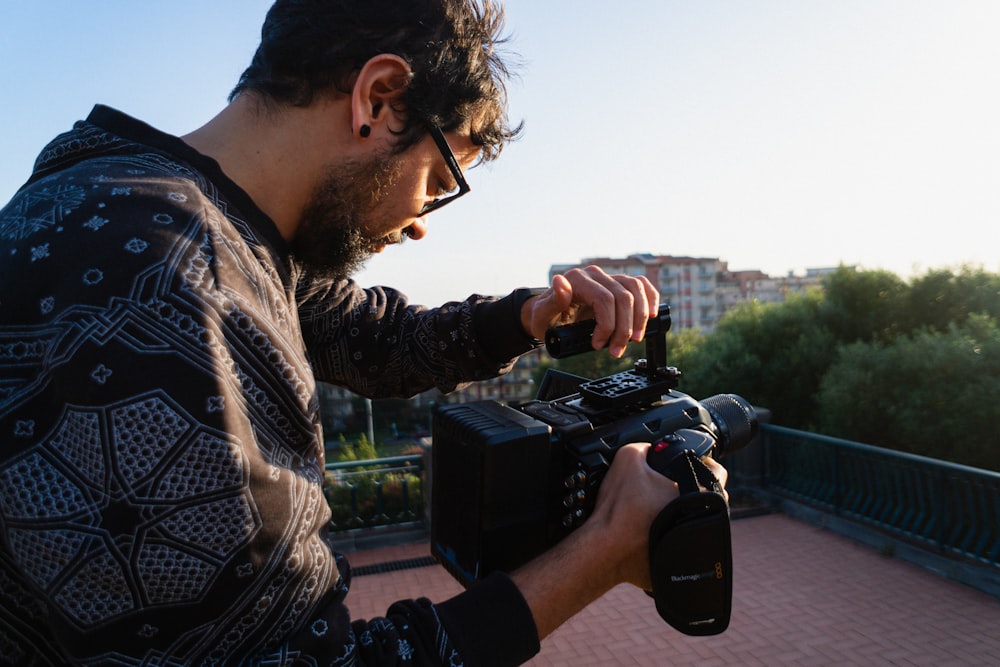 man in black and white plaid dress shirt holding black dslr camera