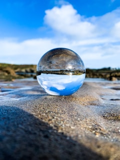 A transparent glass ball reflecting sunlight with a soft background blur.