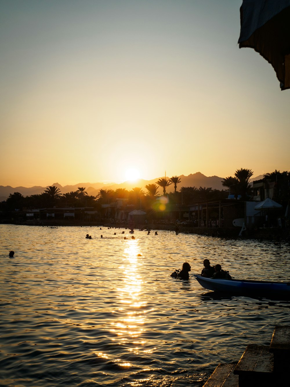 silhouette of people riding boat on body of water during sunset