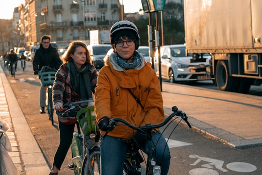 woman in brown jacket riding bicycle during daytime in Quai Saint-Michel France