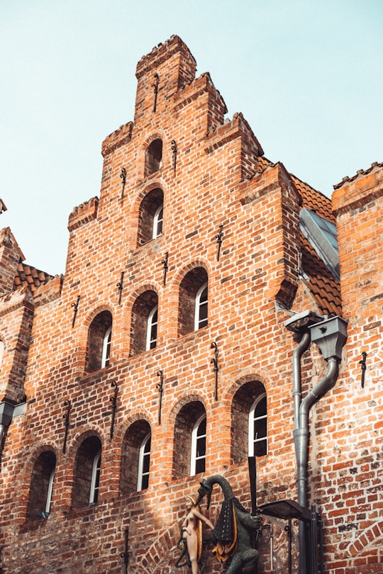 brown brick building under blue sky during daytime in Lübeck Germany