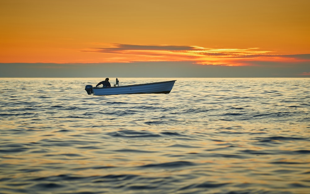 silhouette of person riding on boat during sunset