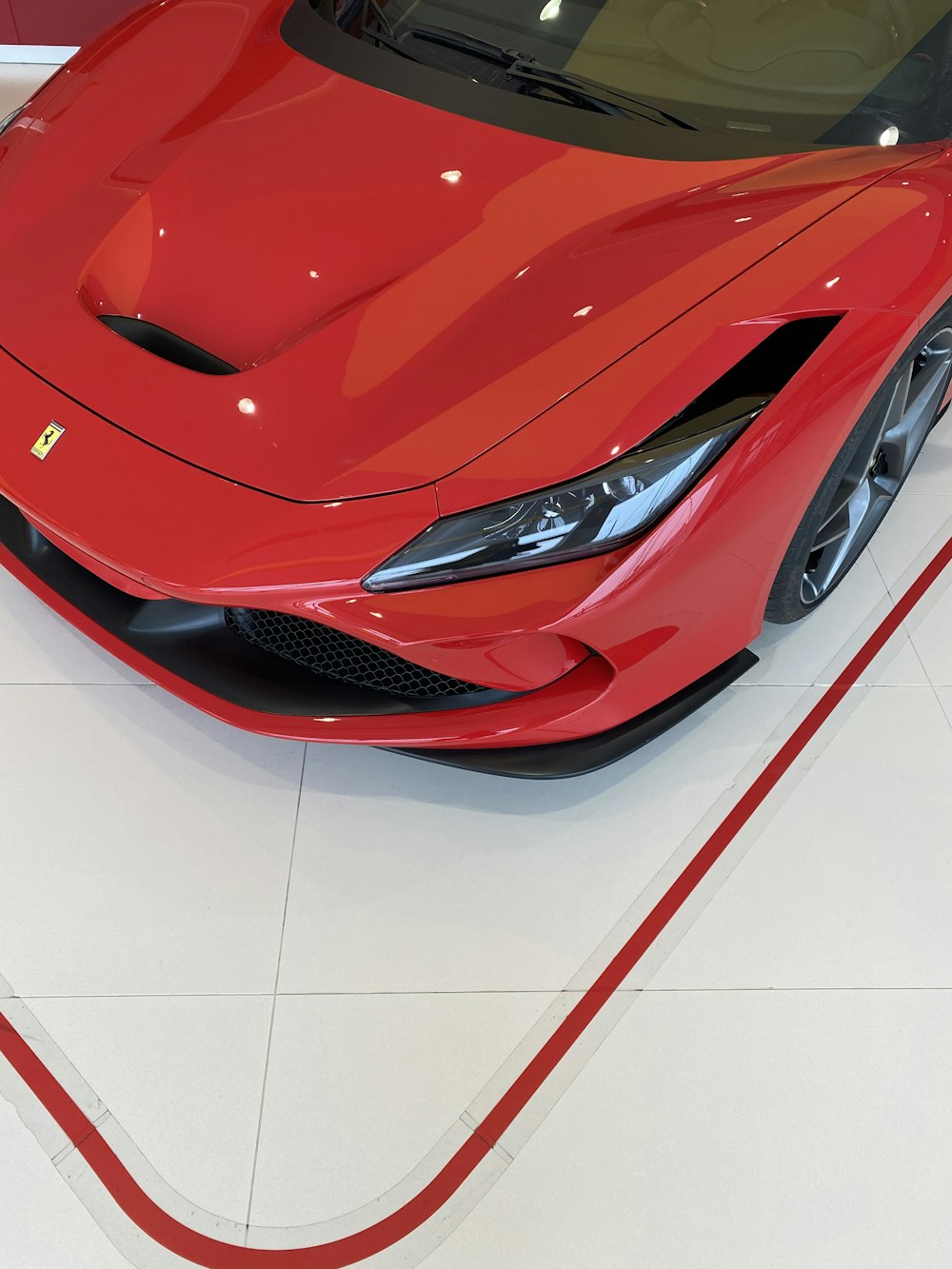 red ferrari car on white floor tiles