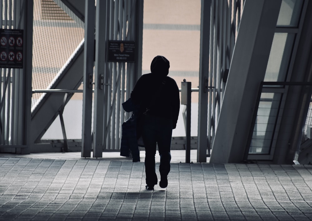 man in black jacket and black pants standing on sidewalk during daytime