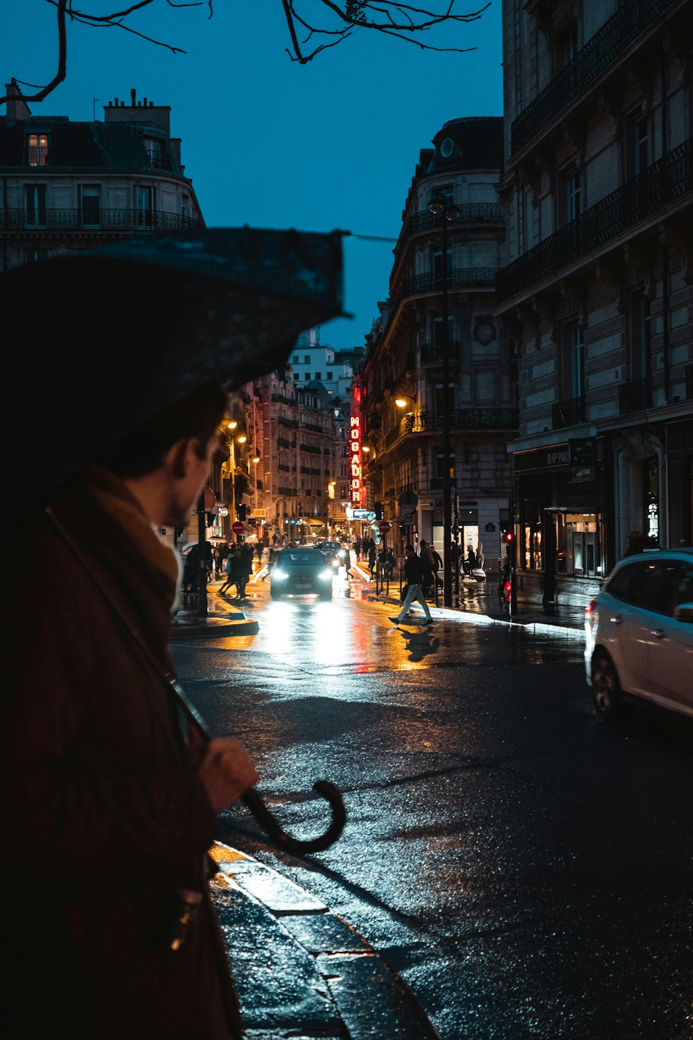 person in brown coat holding umbrella walking on sidewalk during night time