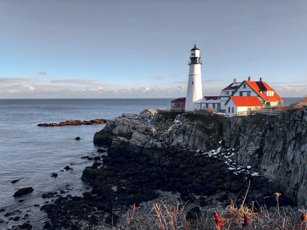 white and black lighthouse on rocky shore during daytime