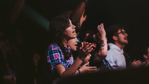 An enthusiastic audience clapping at the Auditorio Metropolitano de Puebla during a live music contest.