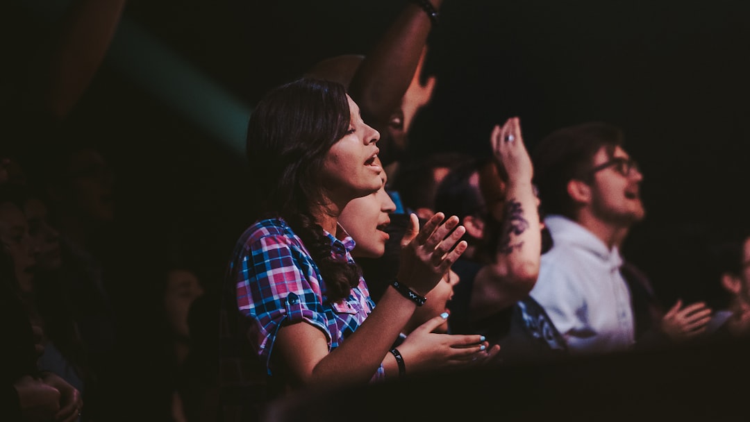 woman in red white and blue plaid shirt smoking cigarette, During a worship service.