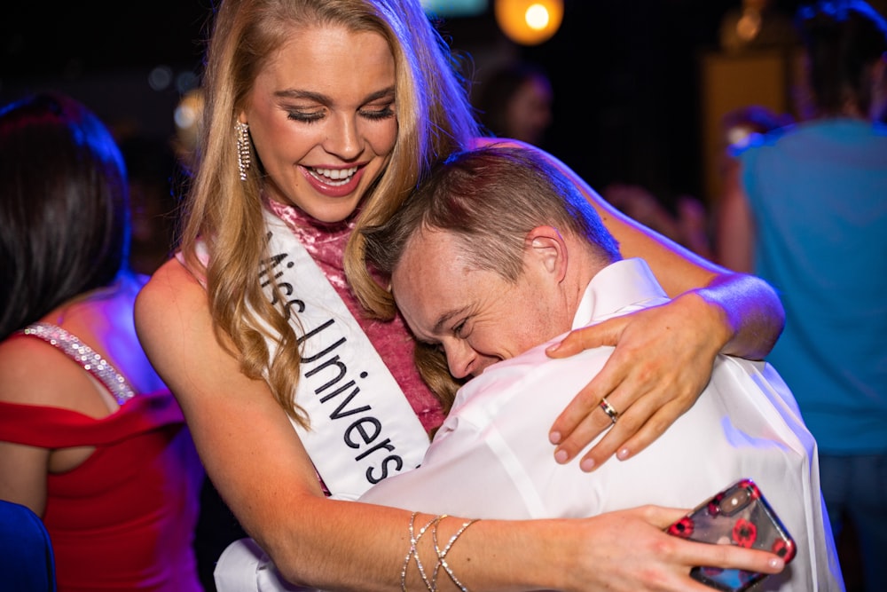 woman in white sleeveless shirt hugging man in white dress shirt