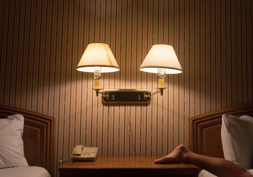 person lying on bed near wall mounted lamp