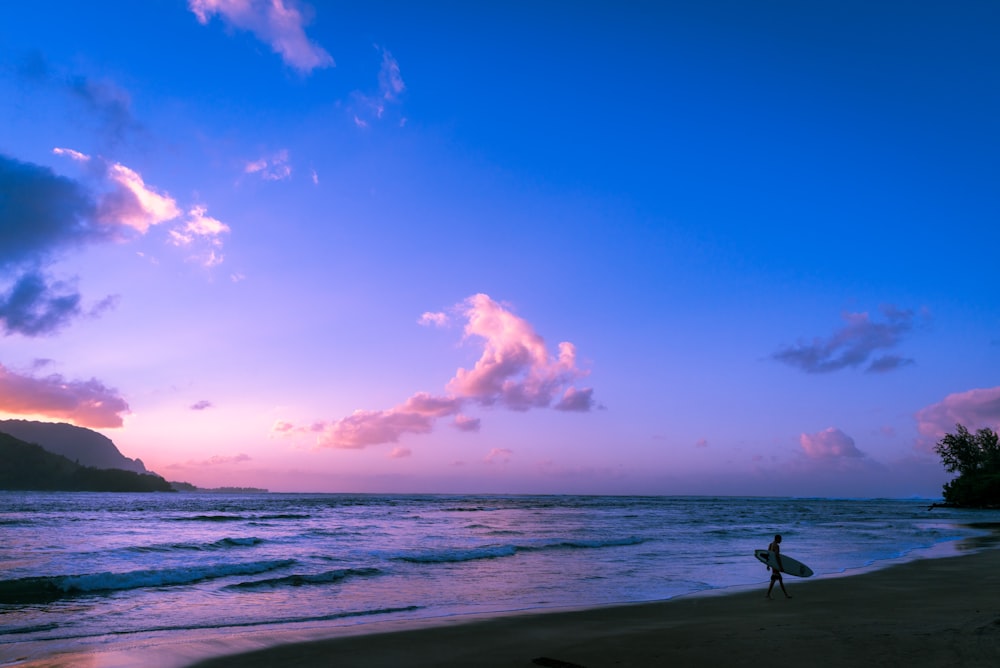 person walking on beach during sunset