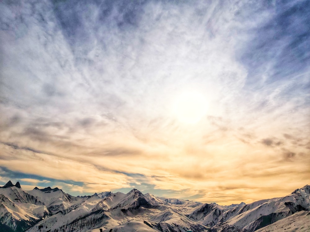 snow covered mountains under cloudy sky during daytime