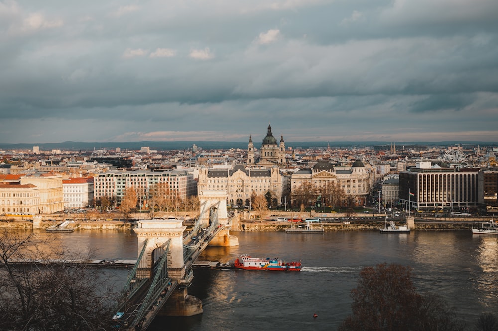 Bateau rouge sur le plan d’eau près du pont et des bâtiments pendant la journée