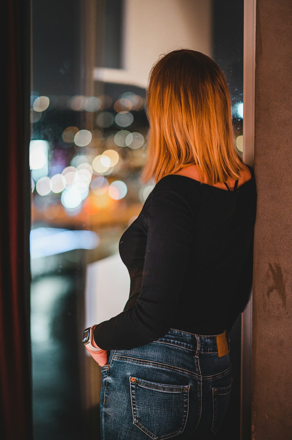 woman in black long sleeve shirt and blue denim jeans standing in front of glass window