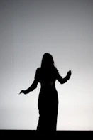 silhouette of woman raising her hands