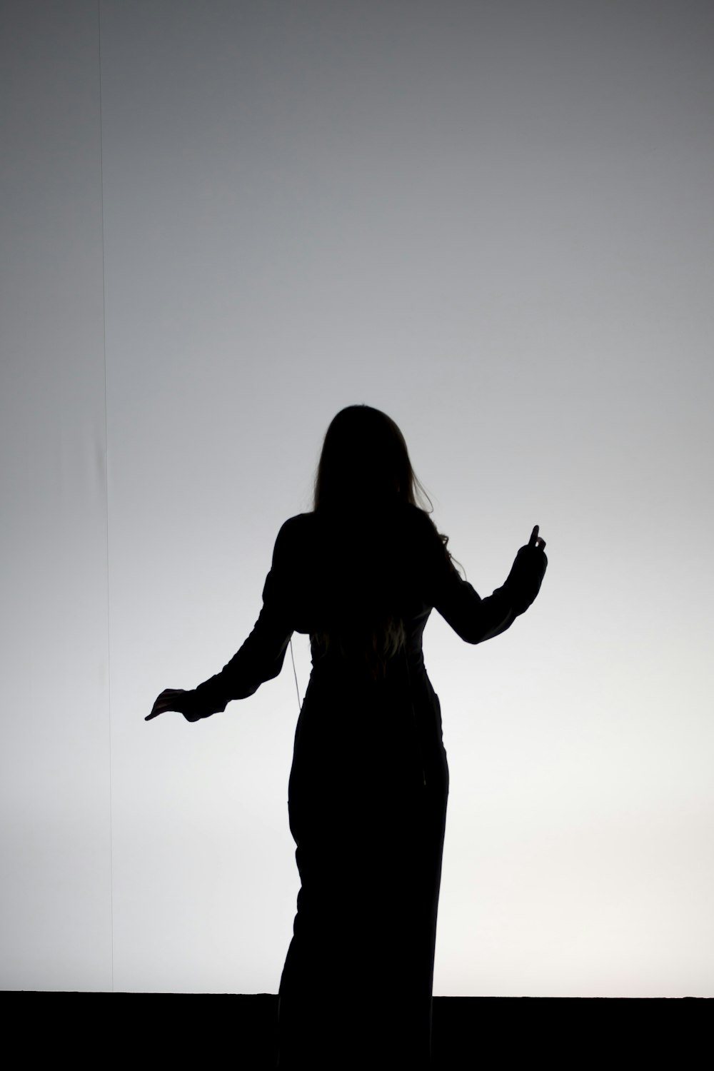 silhouette di donna che alza le mani