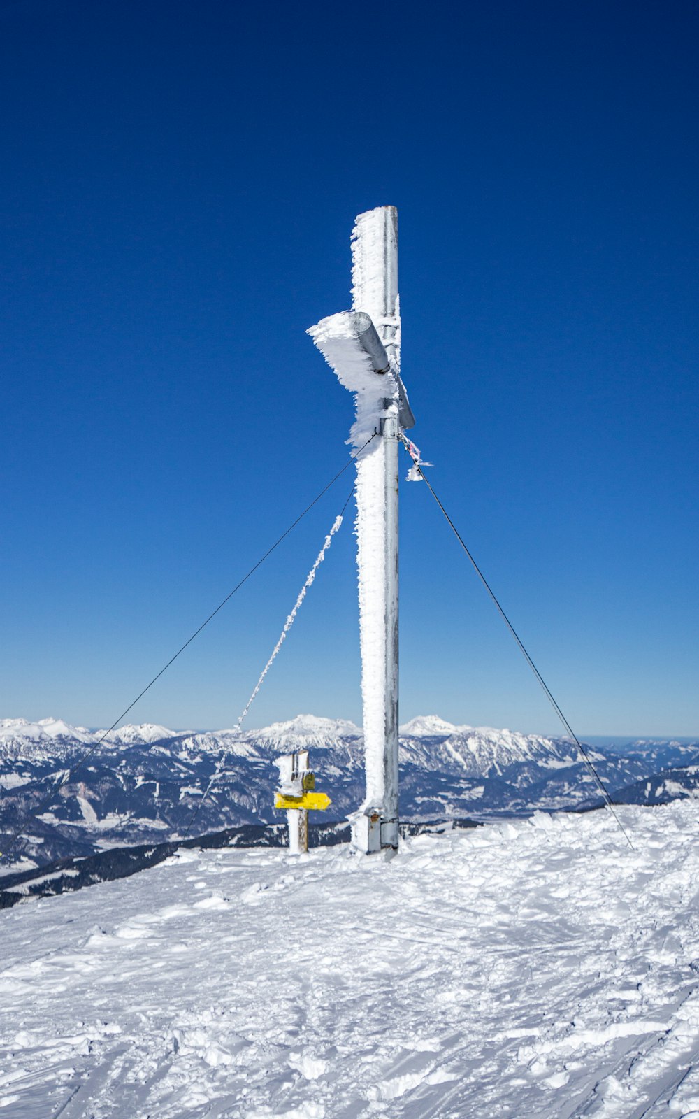 white and yellow metal post on snow covered ground under blue sky during daytime