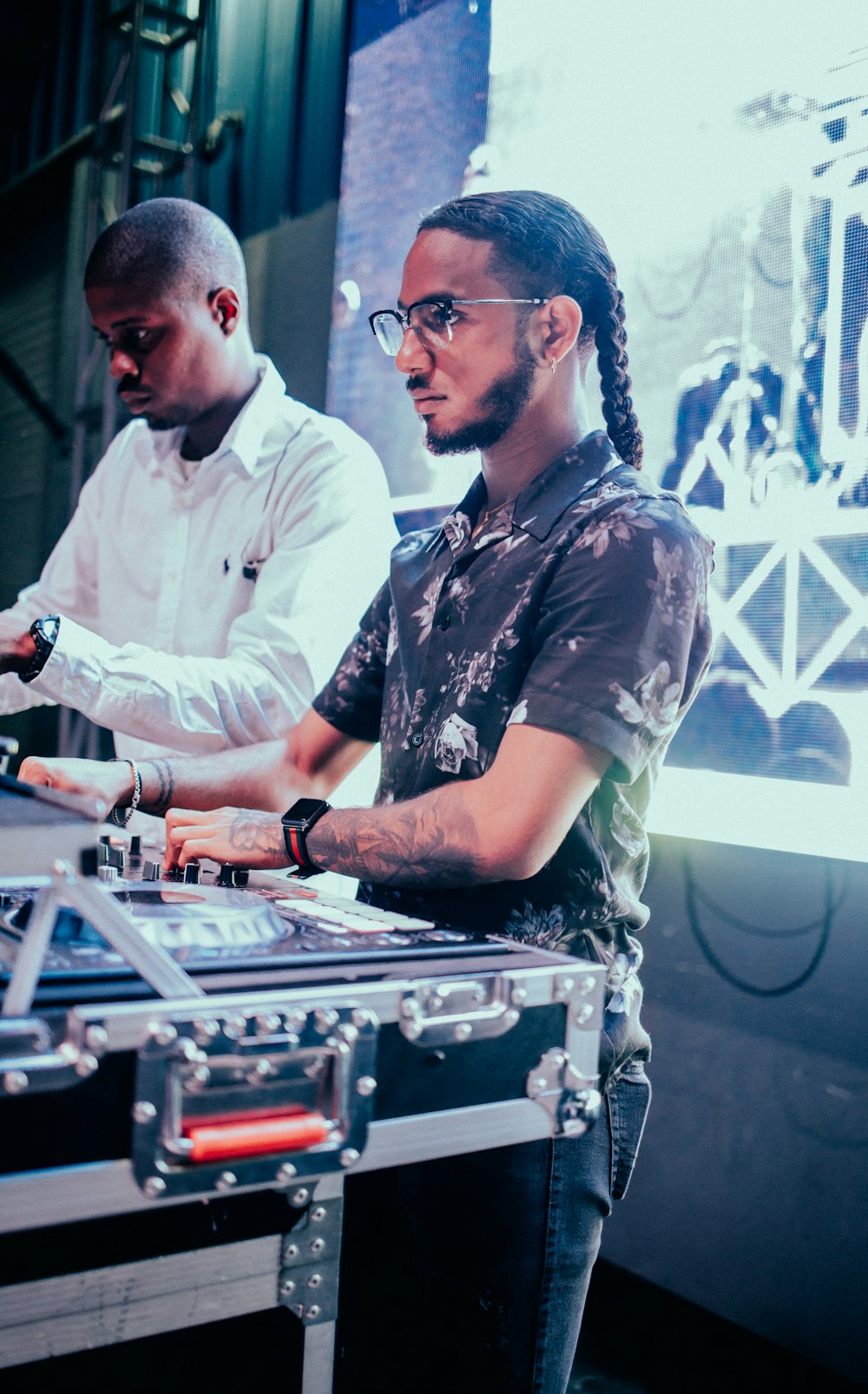 man in black and gray floral button up shirt playing audio mixer