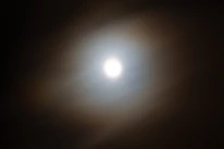 A close-up of a delicate halo of light encircling a shining star in deep blue background.