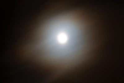 A close-up of a delicate halo of light encircling a shining star in deep blue background.