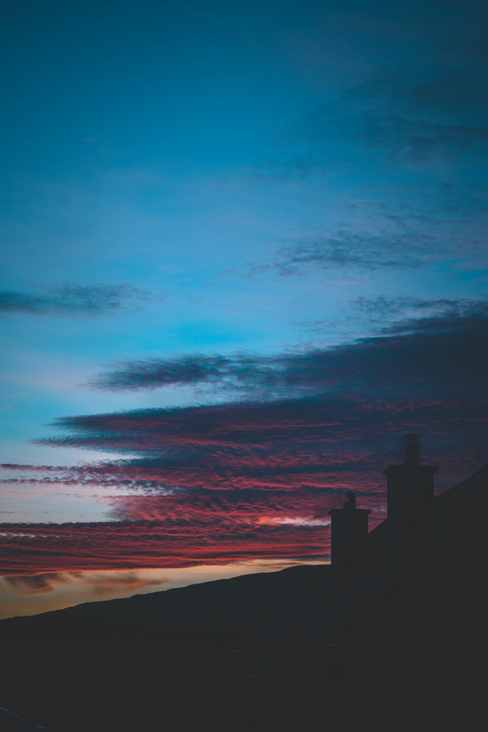 silhouette of building near body of water during sunset