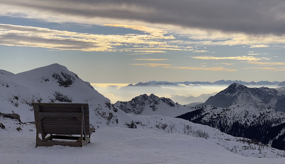 brown wooden bench on snow covered mountain during daytime