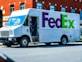 man in green jacket standing beside white and blue van during daytime
