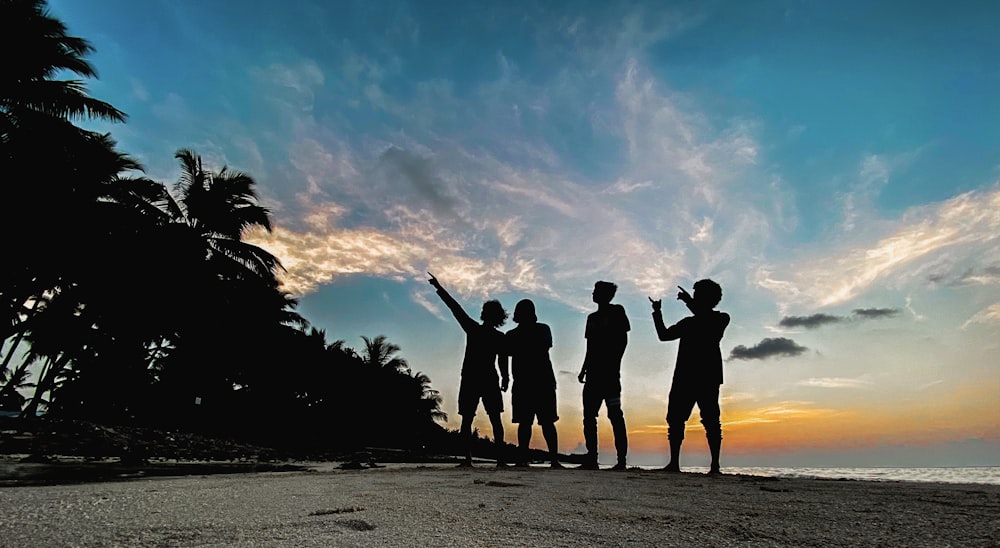 silhouette of people standing on beach during sunset