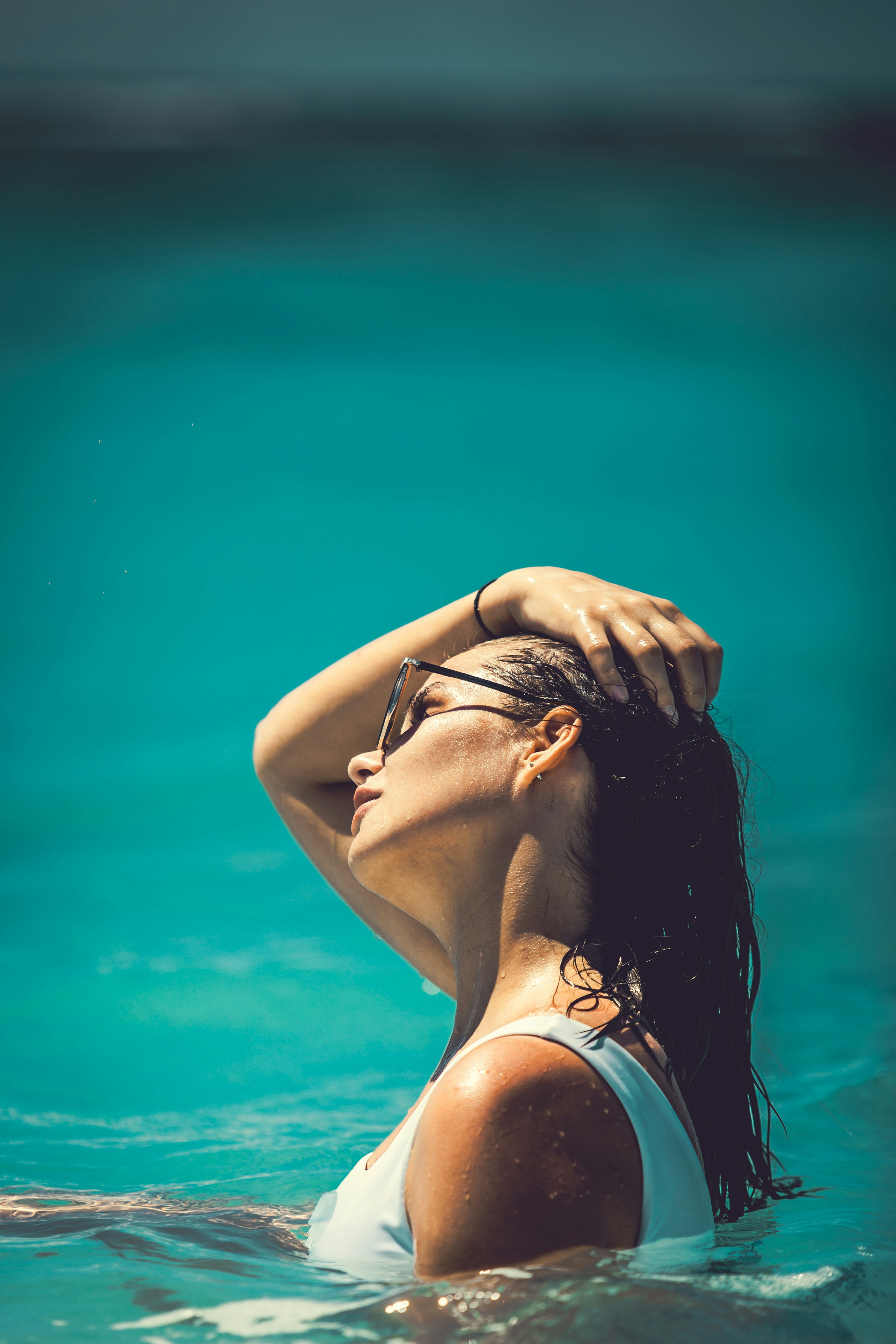woman in white tank top covering her face with her hands