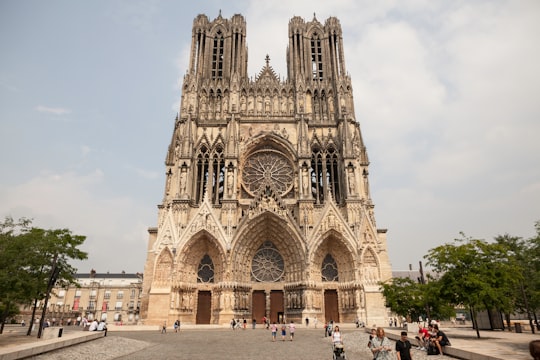 people walking near brown concrete building during daytime in Cathédrale Notre-Dame de Reims France