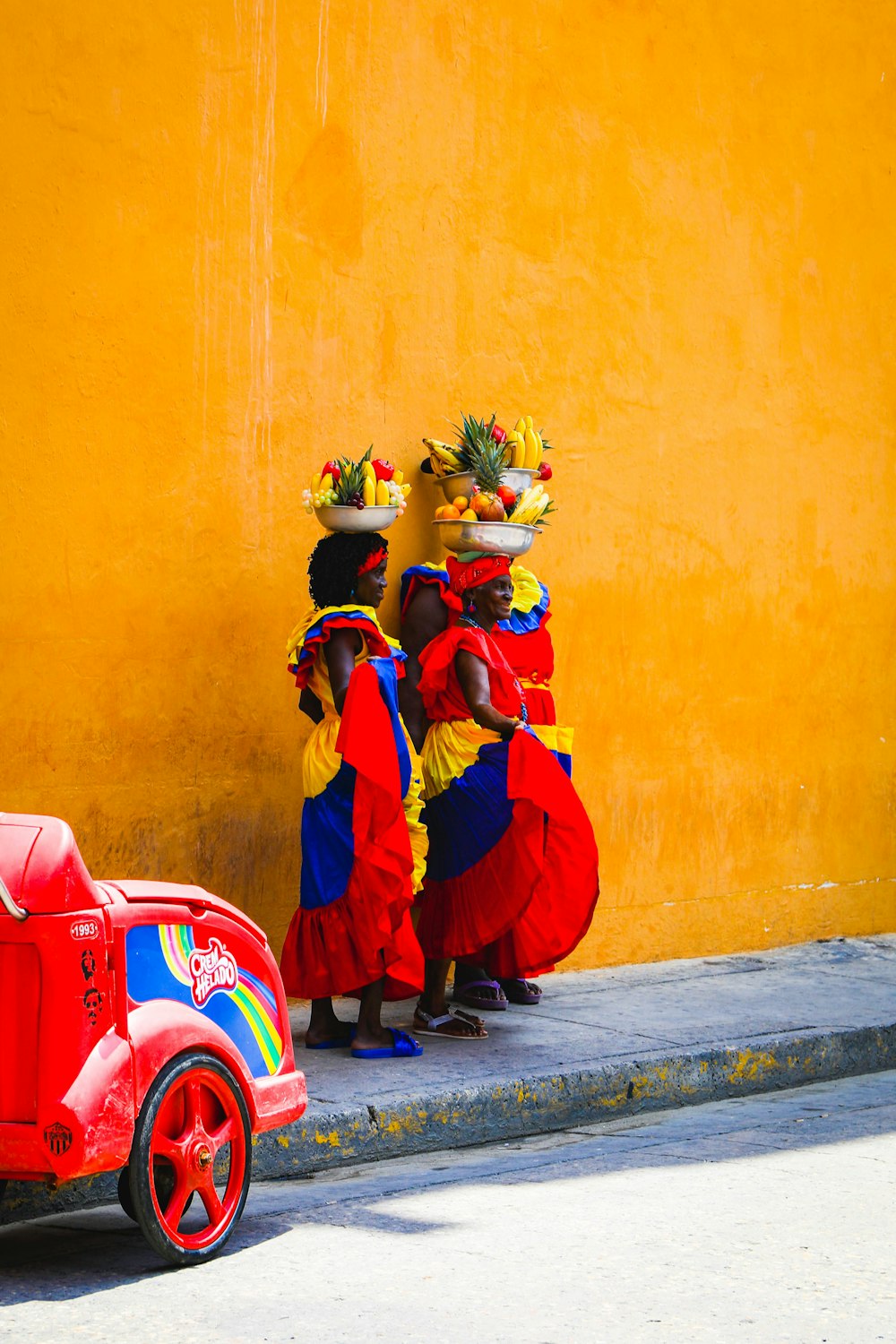 woman in red and yellow dress holding bouquet of flowers