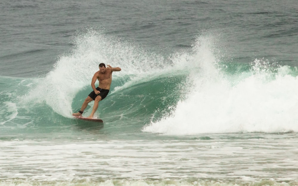 man in black shorts surfing on sea waves during daytime