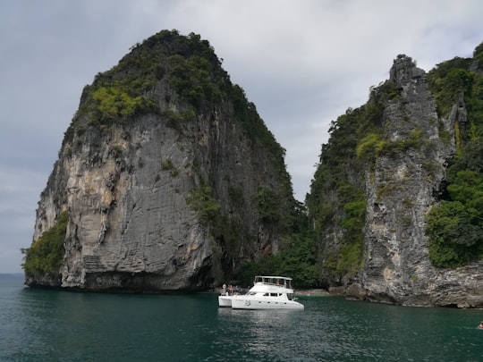 white boat on sea near gray and green rock formation during daytime in Krabi Thailand