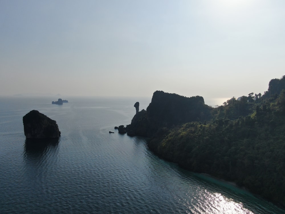 Silhouette der Person, die tagsüber mitten im Meer auf einer Felsformation steht