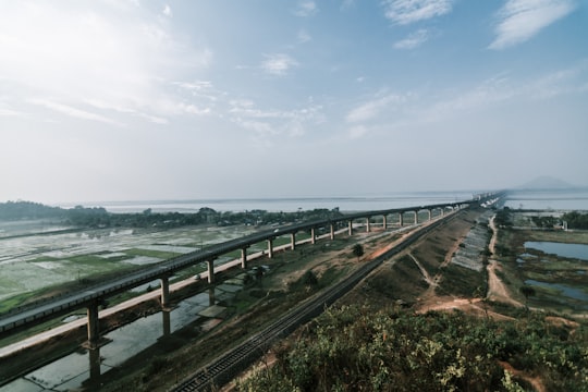 brown wooden bridge over the sea under white clouds during daytime in Naranarayan Setu India