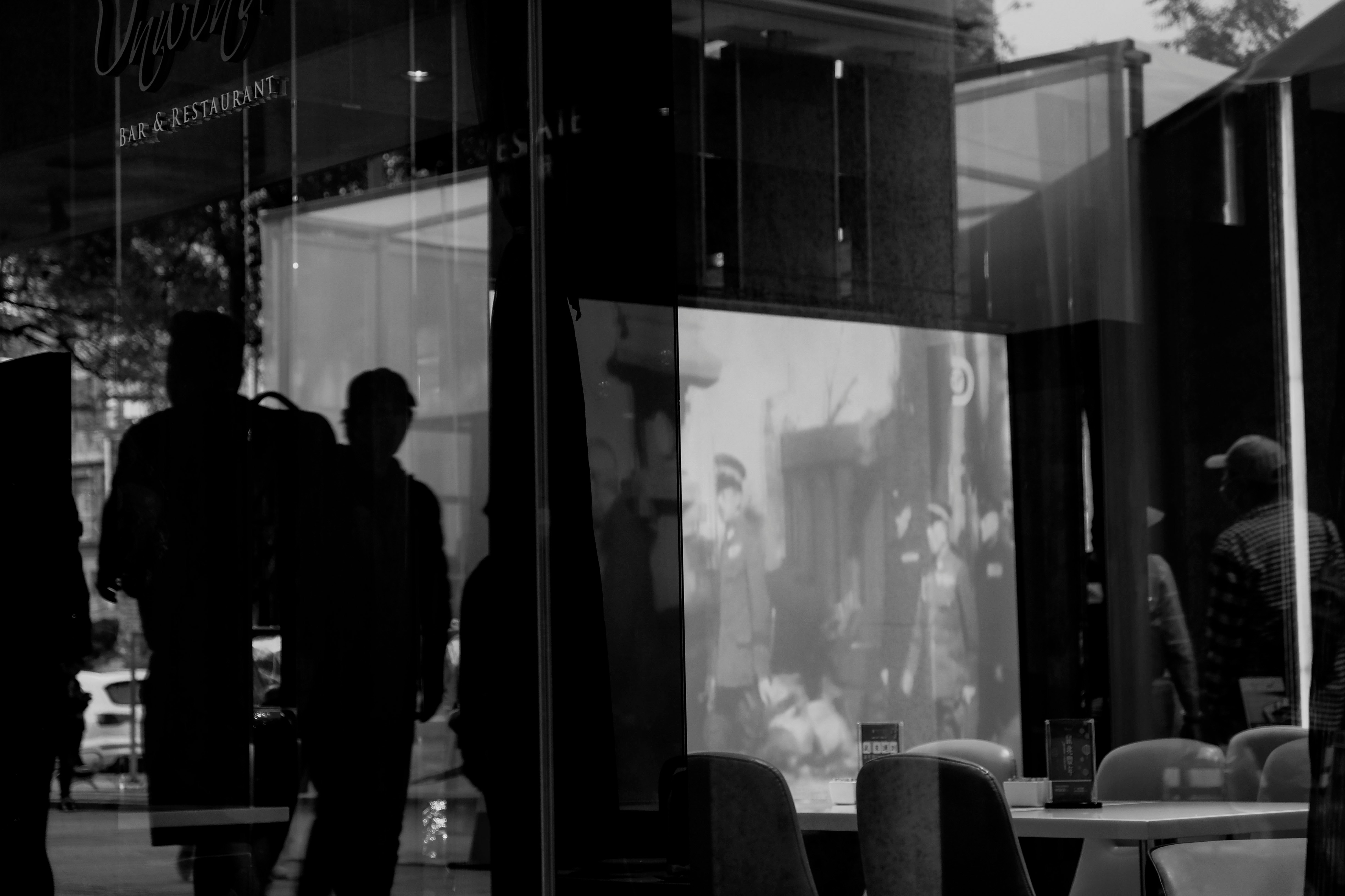 man in black suit standing near glass window