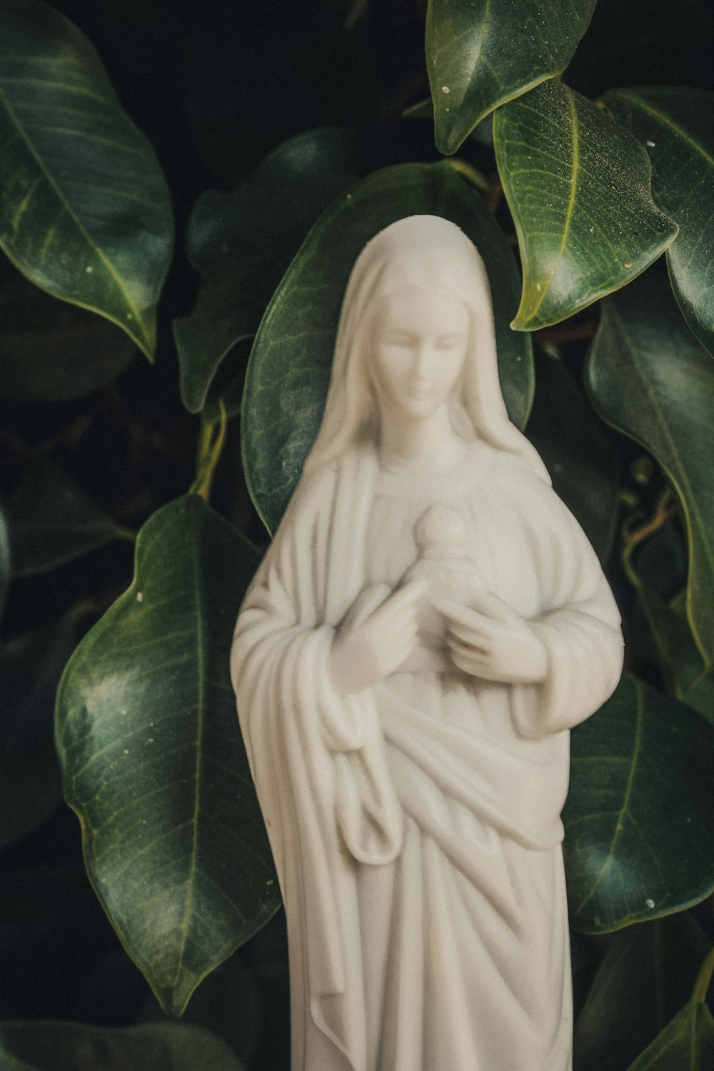 white ceramic angel figurine on green leaves