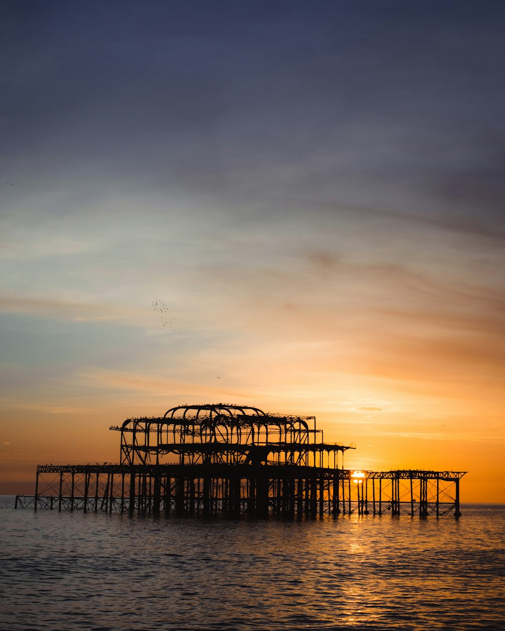 silhouette of wooden dock on sea during sunset