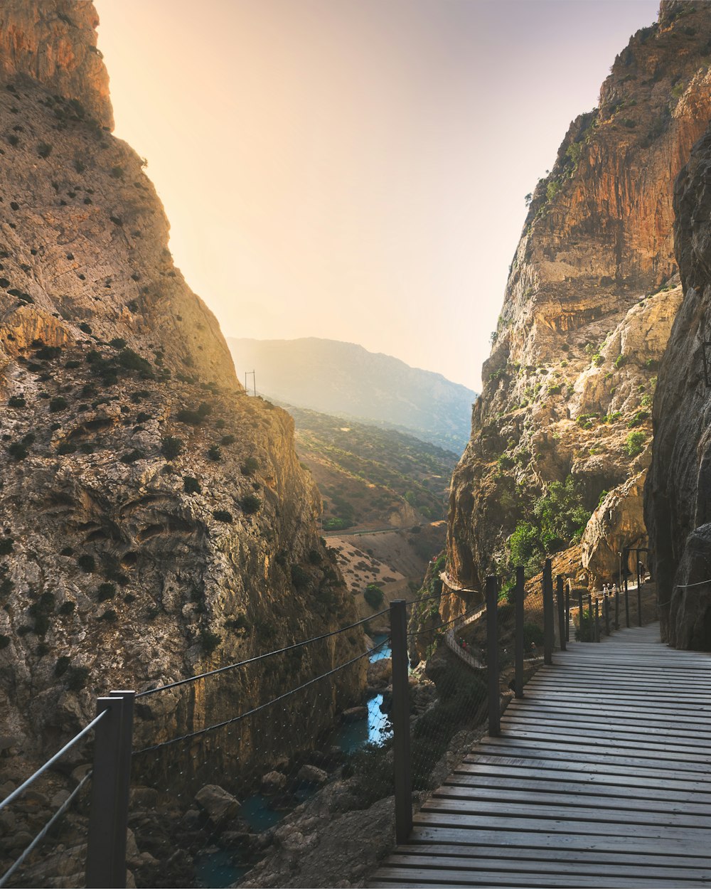 brown wooden bridge between brown rocky mountains during daytime