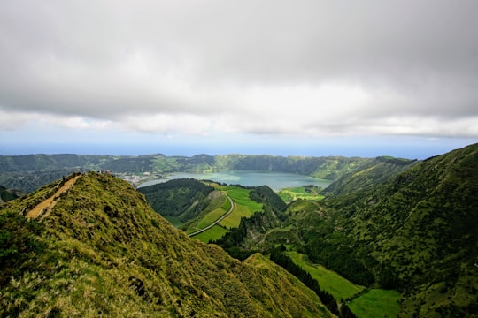 green mountains under white clouds during daytime in Miradouro da Boca do Inferno Portugal