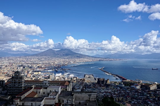city buildings near body of water under blue and white cloudy sky during daytime in Napoli Italy