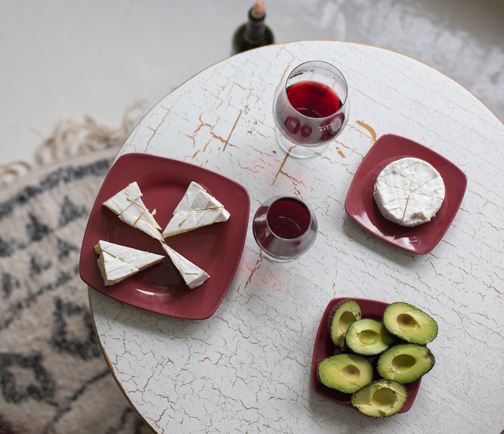 green and red sliced fruits on red and white ceramic plate