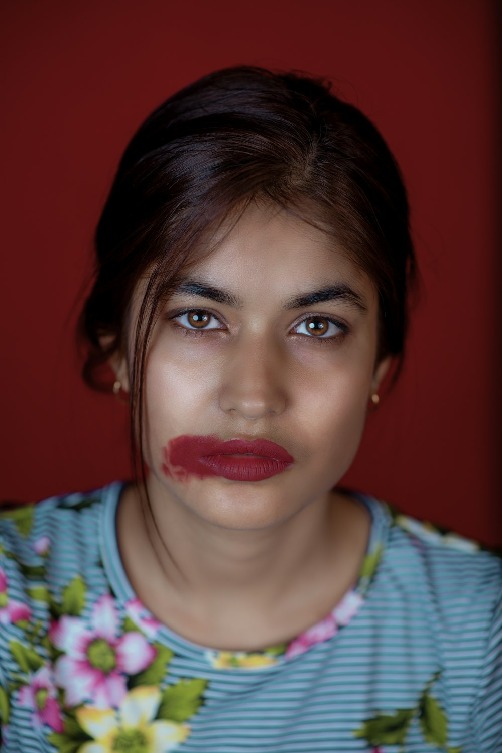 donna in camicia bianca, blu e verde con rossetto rosso