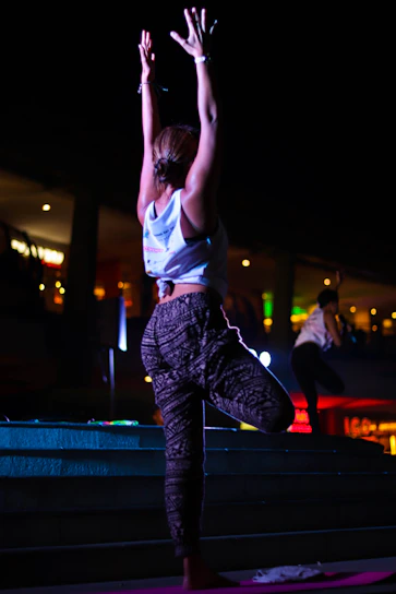 woman in white tank top and black pants jumping on blue yoga mat