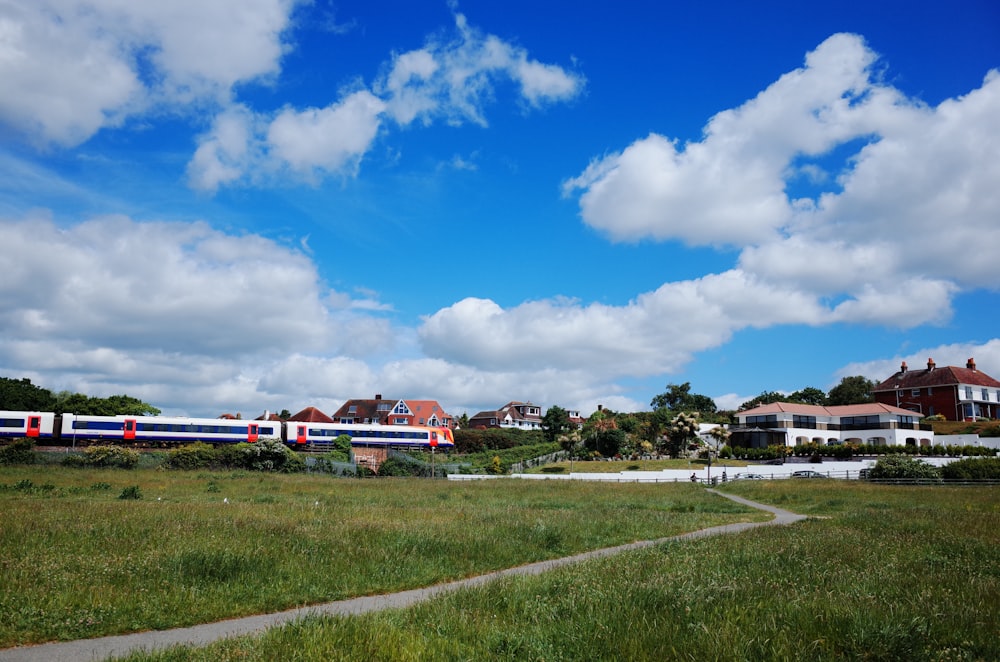 tren rojo y blanco sobre rieles bajo el cielo azul durante el día