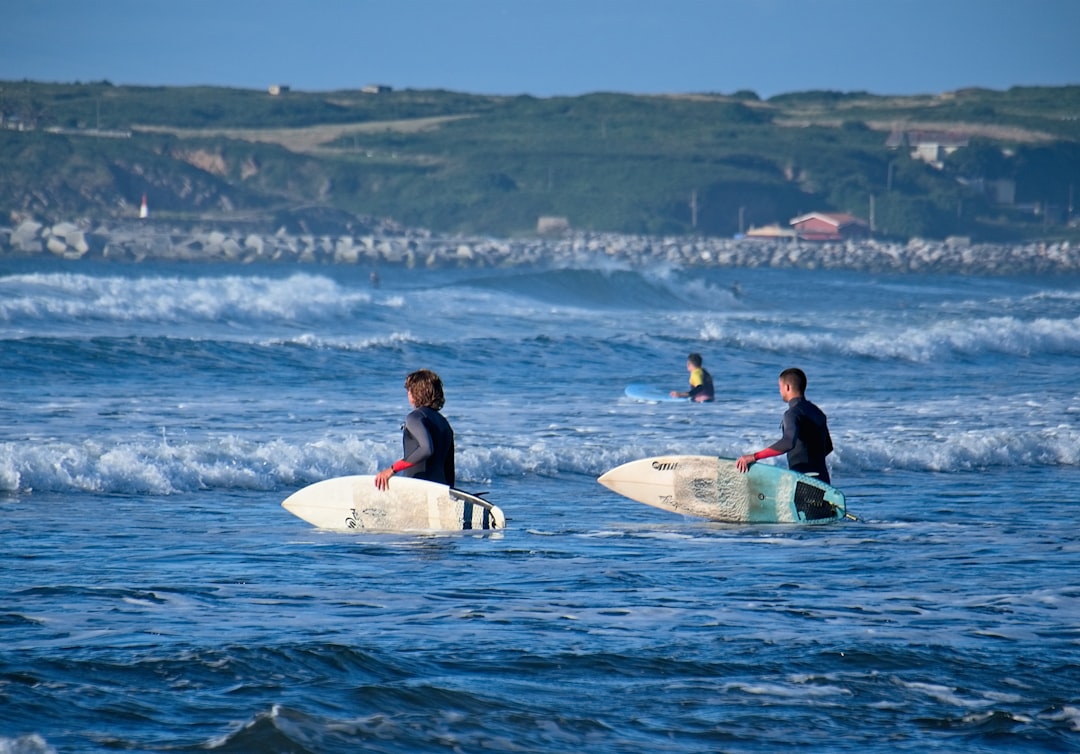 2 women in black wet suit riding white surfboard on sea during daytime