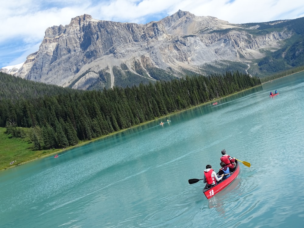 2 people riding on red kayak on lake near mountain during daytime